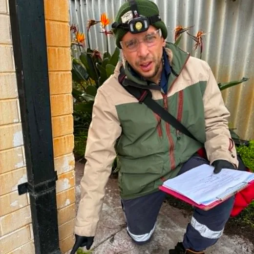 Fabien documenting findings on a clipboard beside a Perth home