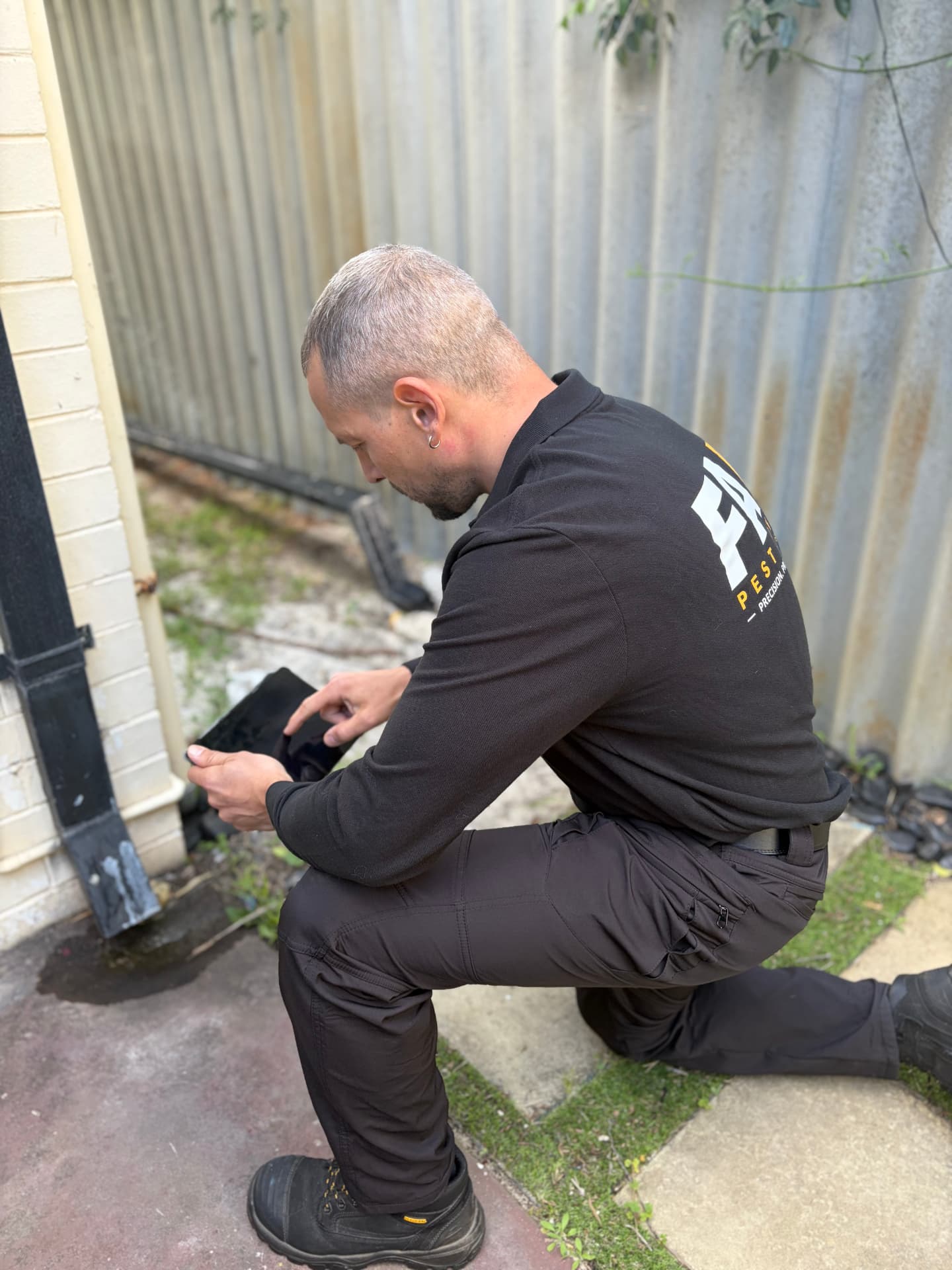 Fabien documenting termite inspection findings on a tablet beside a Perth home